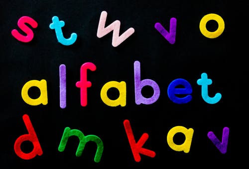 黑色背景上的什锦的彩色alfabet字母 · 免费素材图片