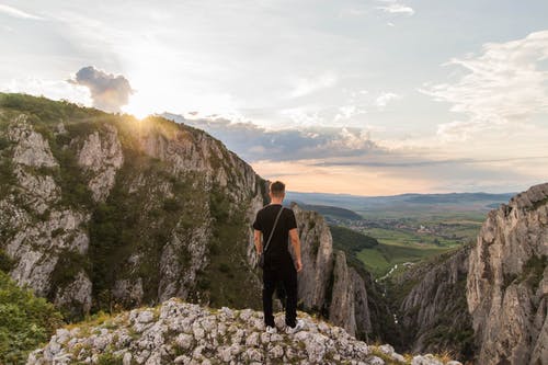 男子站在灰色的山崖上 · 免费素材图片