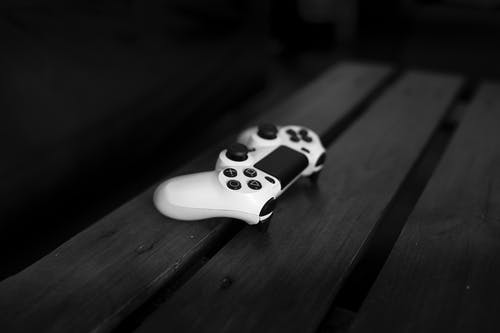 黑色木质表面上的白色sony Dualshock 4控制器 · 免费素材图片
