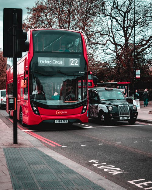 沥青路上黑色出租车旁边的红色双层巴士 · 免费素材图片