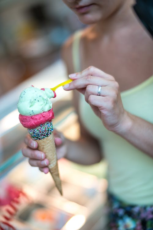 女人在锥体拿冰淇淋的选择性焦点摄影 · 免费素材图片