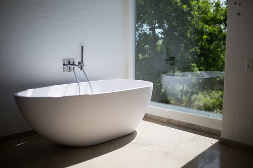 透明玻璃墙旁的白色陶瓷浴缸 · 免费素材图片