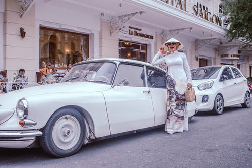 女人站在经典的白色轿车旁边 · 免费素材图片