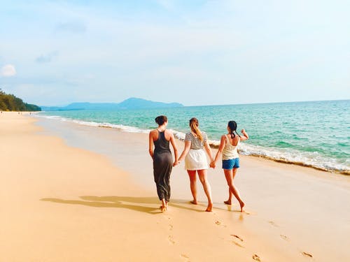 三名女子在蔚蓝的天空在海边散步 · 免费素材图片