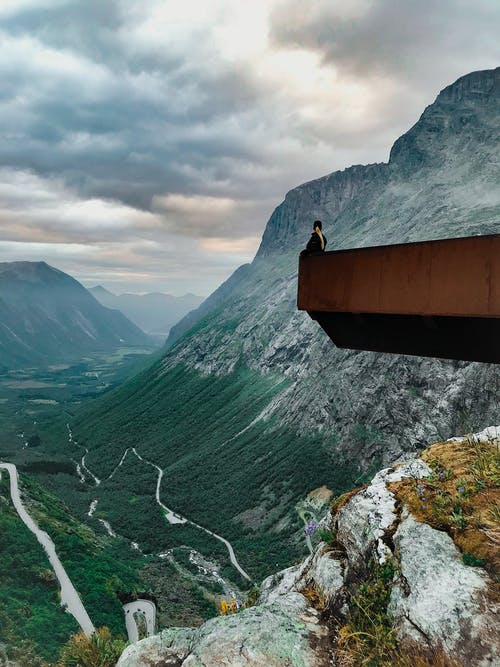 男人坐在石头上的边缘 · 免费素材图片