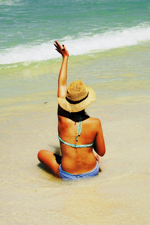 女人坐在岸边挥舞着的手 · 免费素材图片