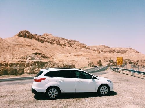 土层附近土路上的白色越野车 · 免费素材图片