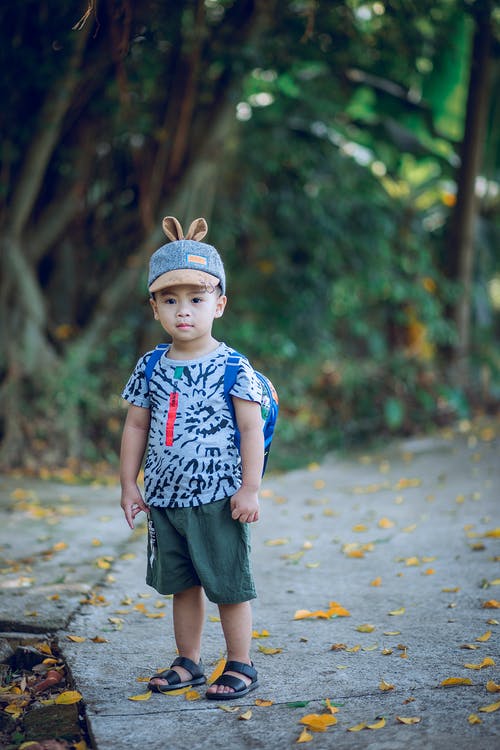 男孩穿着衬衫和背包站在混凝土通路上 · 免费素材图片