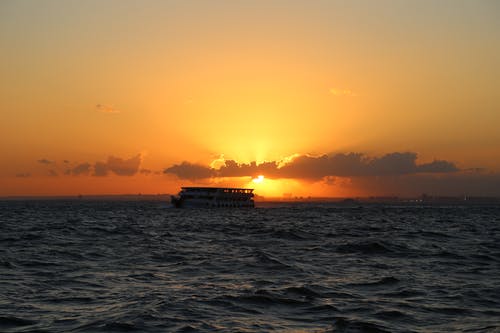 日落期间巡洋舰船在水体上的剪影摄影 · 免费素材图片