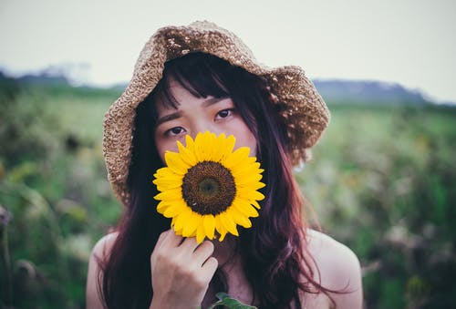 持有向日葵的棕色太阳帽的女人 · 免费素材图片