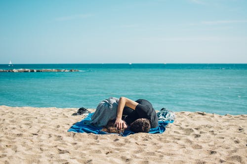 男人和女人躺在海边的蓝色纺织 · 免费素材图片