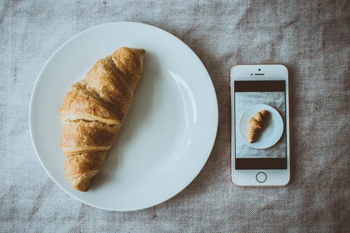 玫瑰金iphone Se旁边的圆形白板上的牛角面包，在板上显示牛角面包的照片 · 免费素材图片