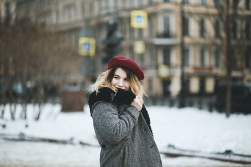 女人在下雪天穿外套和红色的帽子 · 免费素材图片