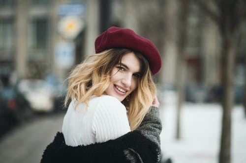 在下雪天戴红色帽子的微笑妇女的选择性焦点摄影 · 免费素材图片