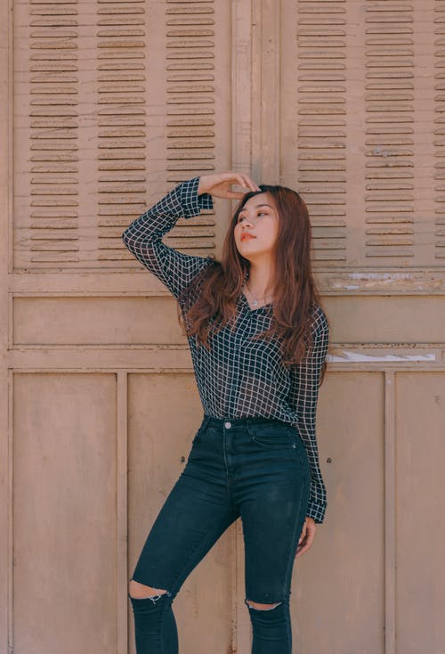 女人站在棕色的墙附近 · 免费素材图片