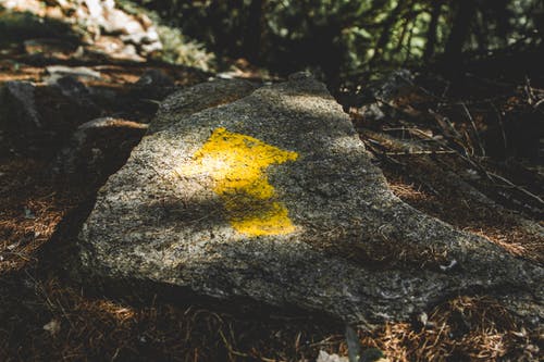 黄色箭头画在灰色的石头上 · 免费素材图片