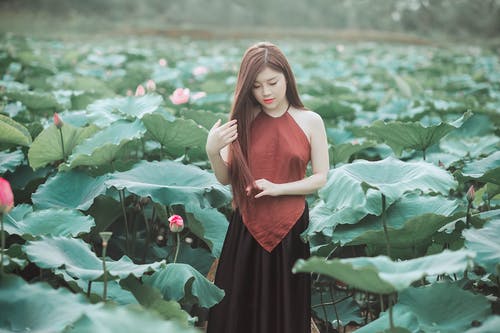 红色吊带衫站在农场场上的女人 · 免费素材图片