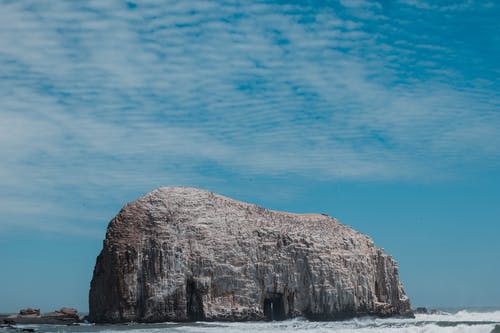 蓝蓝的天空下的海滩上的灰色岩层 · 免费素材图片