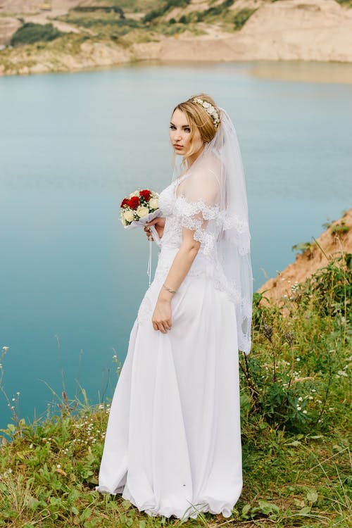 在湖前抱着花束的婚纱的女人 · 免费素材图片