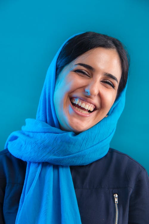 女人微笑着靠在蓝墙上 · 免费素材图片