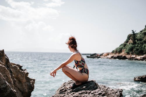 坐在岩石上的泳衣的女人 · 免费素材图片