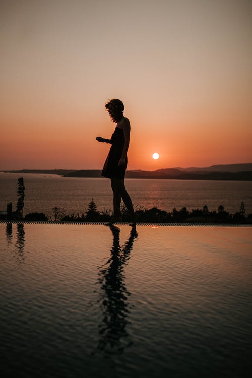 人站在游泳池边的剪影摄影 · 免费素材图片