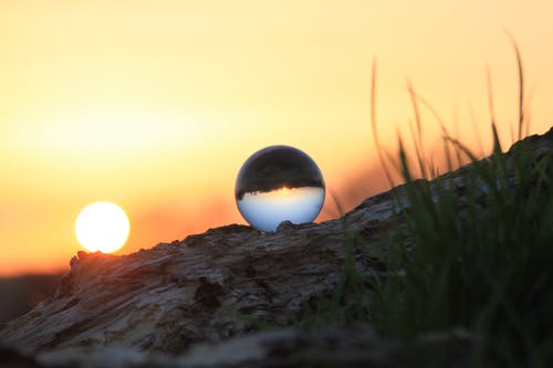 玻璃球在日落期间的棕色岩石形成上的摄影 · 免费素材图片