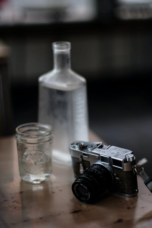 水杯旁边的黑色和灰色相机 · 免费素材图片