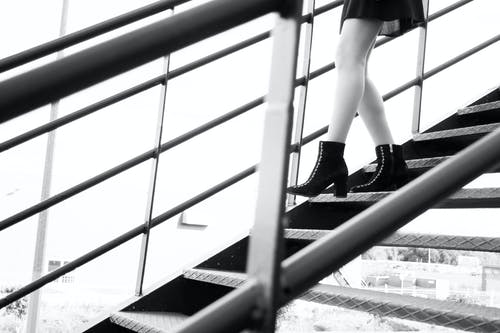 女人在楼梯上行走的灰度摄影 · 免费素材图片