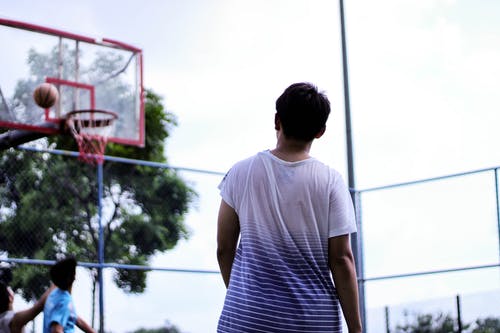 男子站在红色篮球架系统附近 · 免费素材图片