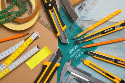 胶带卷附近的透明和绿色olfa测量工具上的各种类型和尺寸的实用刀具 · 免费素材图片