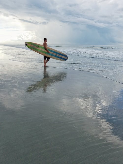 男子盯着大海时，抱着冲浪板 · 免费素材图片