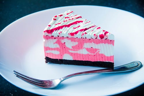 在白板上用银色叉子切成薄片的白色和粉红色糖衣覆盖蛋糕 · 免费素材图片