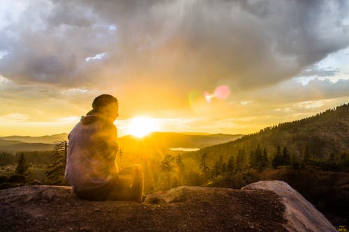 人坐在石头面对日落 · 免费素材图片