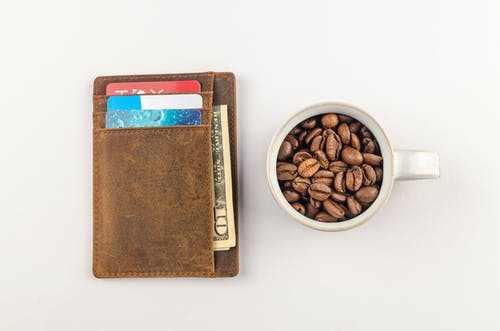 白色杯子与棕色钱包旁边的咖啡豆 · 免费素材图片