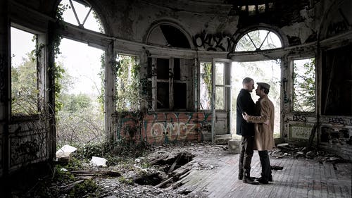 两名男子站在失事大楼内的棕色地板上 · 免费素材图片