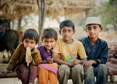 四个孩子坐在棕色charpai床上 · 免费素材图片