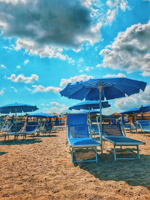 蓝色阳伞和沙滩上的太阳椅 · 免费素材图片