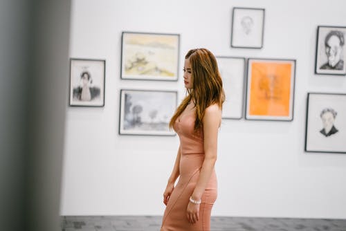 女人站在墙上的画附近 · 免费素材图片