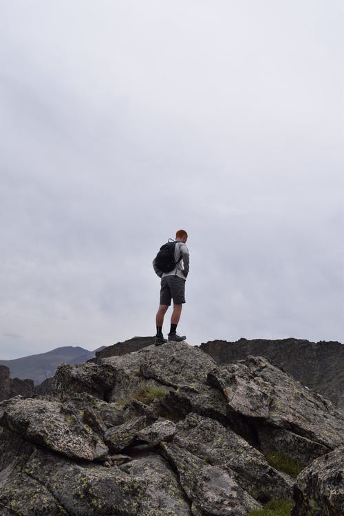 黑色背包站在岩石上的男人 · 免费素材图片