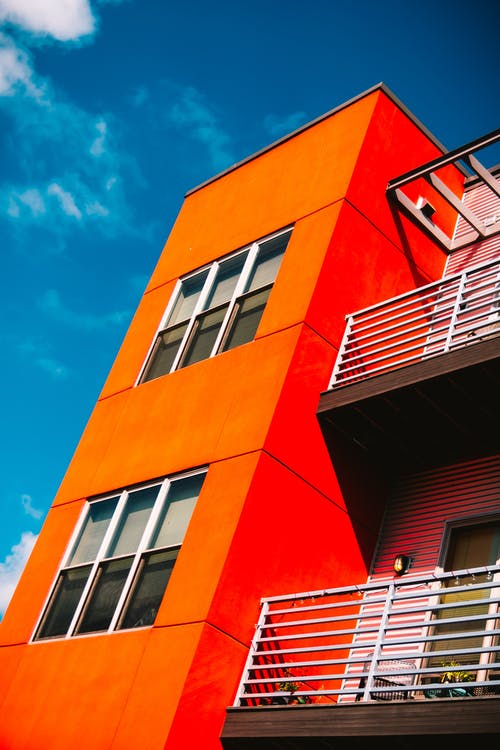 蓝天白云下的橙色混凝土建筑的低角度摄影 · 免费素材图片