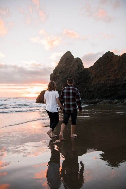 夫妻在岸边散步时握着彼此的手 · 免费素材图片