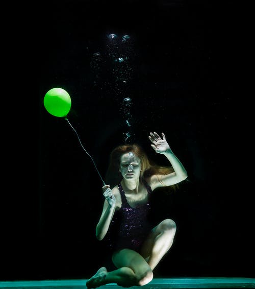女人拿着绿色气球的水下摄影 · 免费素材图片