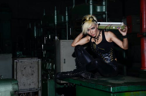 女人坐在绿色金属工业机器 · 免费素材图片