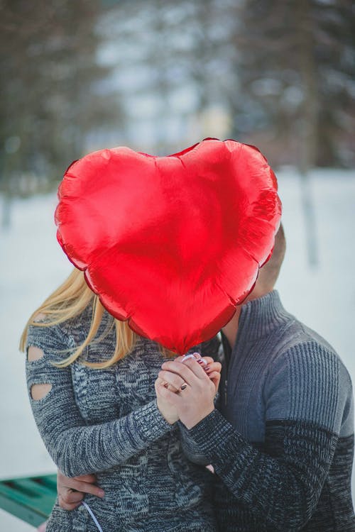 情侣手牵着手与红色心形气球 · 免费素材图片