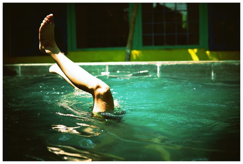 人在游泳池里游泳，脚在空中 · 免费素材图片