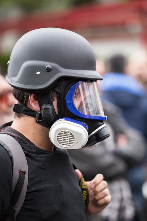 戴着黑色防毒面具和防护头盔的人 · 免费素材图片