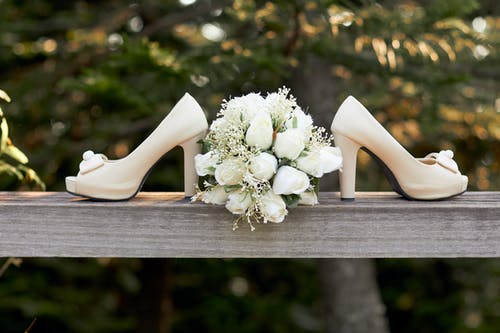 一双白色露趾矮胖高跟鞋和束鲜花的选择性聚焦摄影 · 免费素材图片