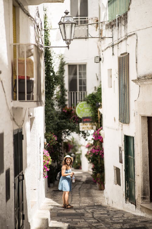 女人站在房子包围的通路上 · 免费素材图片