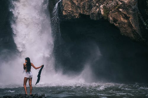女人站在瀑布附近 · 免费素材图片